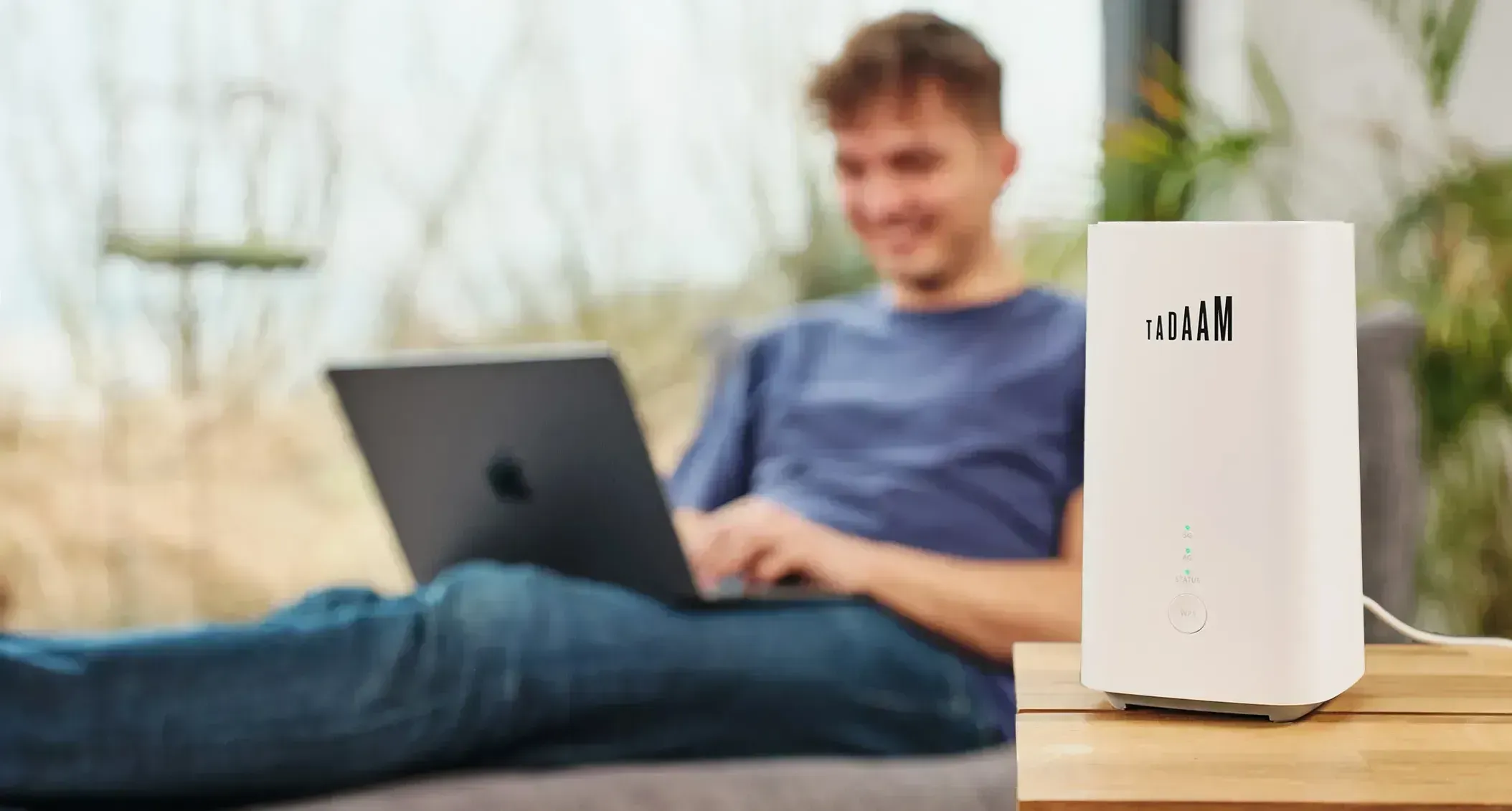 An image of a man working on a laptop with a TADAAM modem next to him.